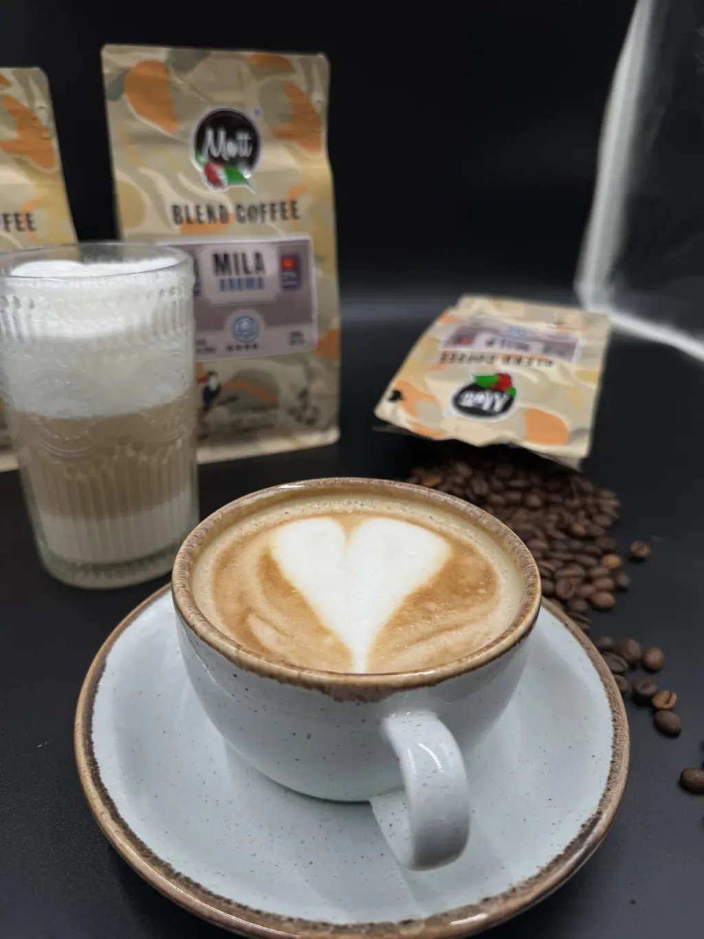 Latte with a heart in the milk foam next to a bag of Mott Coffee beans