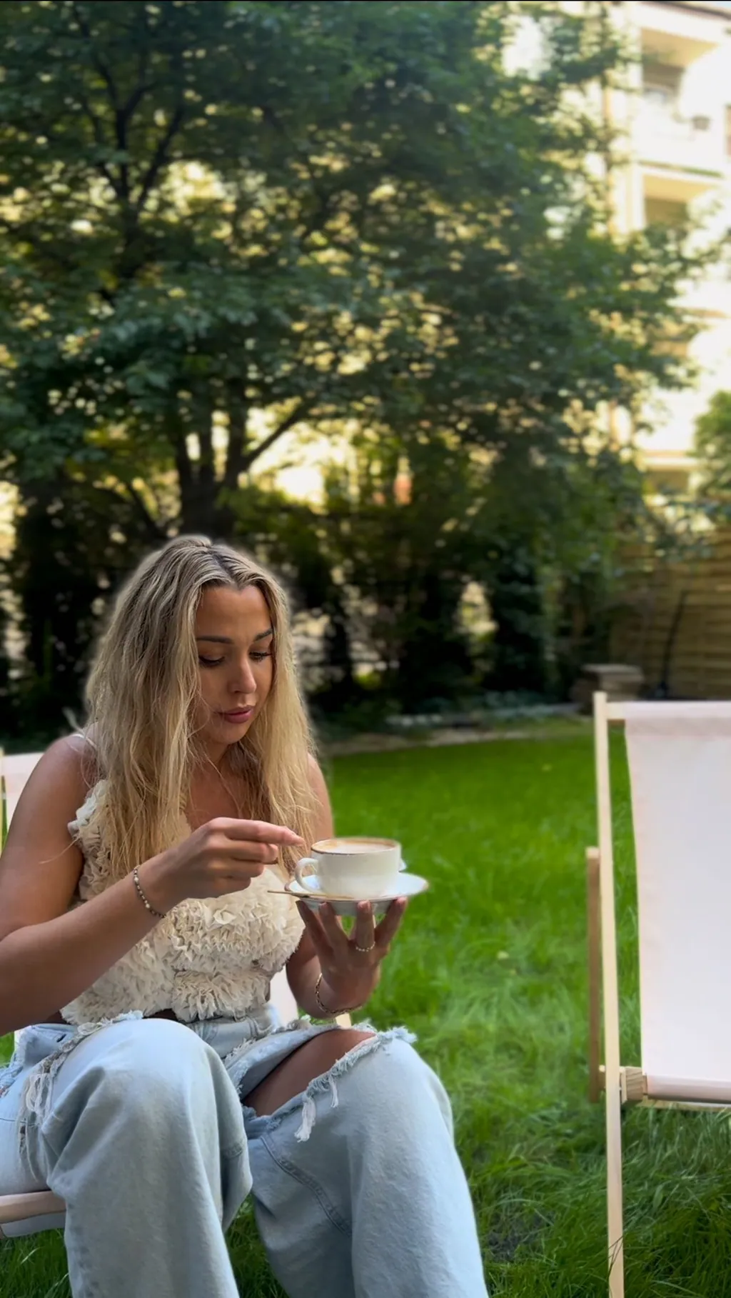 A guest with a cup of coffee in a deck chair in the garden